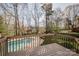 Beautiful backyard pool and deck area with mature trees and a charming fence, perfect for relaxing and entertaining at 8718 Canter Post Dr, Charlotte, NC 28216
