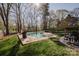 A sparkling pool with a surrounding patio is nestled in a yard with mature trees and green grass at 8718 Canter Post Dr, Charlotte, NC 28216