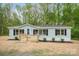 Charming home featuring a light blue exterior, a wooden deck, and black shutters against a backdrop of lush trees at 102 Lansdale Ave, Lincolnton, NC 28092