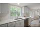 This bright kitchen has a modern sink, white cabinets and countertops and a window overlooking greenery at 102 Lansdale Ave, Lincolnton, NC 28092