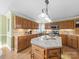 A spacious kitchen with oak cabinetry and a granite island is lit by pendant lights and natural light from the window at 106 Berea Baptist Church Rd, Stanfield, NC 28163
