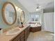 Relaxing main bathroom with dual sinks, large mirrors, and a soaking tub surrounded by tile at 106 Berea Baptist Church Rd, Stanfield, NC 28163