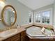 Inviting bathroom with a jacuzzi tub with windows, tile surround, and elegant vanity at 106 Berea Baptist Church Rd, Stanfield, NC 28163