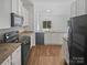 Well-lit kitchen with granite counters, stainless appliances, white cabinets and hardwood style flooring at 1235 Culver Spring Way, Charlotte, NC 28215