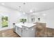 Bright kitchen featuring a center island with stainless steel sink, white cabinetry, and hardwood floors at 12437 Walker Dr # 89, Stanfield, NC 28163