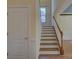 Carpeted stairway with wooden handrail and white trim detailing and natural lighting at 14103 Grand Traverse Dr, Charlotte, NC 28278