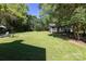 Spacious backyard featuring a large grassy area, mature trees, and a quaint storage shed at 2404 Finchley Dr, Charlotte, NC 28215