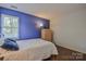A bright bedroom showcasing a simple bed and wooden floors against blue and gray walls at 2731 Bishopton Pl, Charlotte, NC 28216