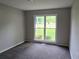 Cozy bedroom featuring gray carpet and a window overlooking the well-maintained lawn at 413 Parallel Dr, Harrisburg, NC 28075