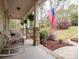 Spacious front porch with rocking chairs, stone pillars, an American flag, and manicured landscaping at 6108 Mcilwaine Rd, Huntersville, NC 28078