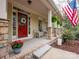 Cozy front porch featuring a red door, rocking chairs, brick accents, and welcoming decor at 6108 Mcilwaine Rd, Huntersville, NC 28078