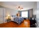 Comfortable bedroom with hardwood floors, ceiling fan, ample natural light from the window, and a blue patterned bedspread at 8621 Sequoia Grove Ln, Charlotte, NC 28214