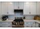 Kitchen detail showcasing stainless steel stovetop, subway tile backsplash, and white cabinets at 8621 Sequoia Grove Ln, Charlotte, NC 28214