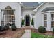 Elegant home entrance with a black front door, trimmed bushes and foliage, sidelights, and decorative window above at 9118 Pine Springs Ct, Huntersville, NC 28078