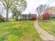 Expansive backyard with a stone walkway, screened-in porch, and colorful landscaping at 11 Tallassee St, Badin, NC 28009