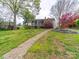 Beautiful backyard with a stone walkway leading to a home with a screened-in porch and lush landscaping at 11 Tallassee St, Badin, NC 28009