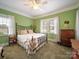 Bright bedroom with green walls, a decorative metal bed frame, and abundant natural light at 11 Tallassee St, Badin, NC 28009