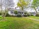 Charming single-story home featuring a brick walkway, lush lawn, and mature trees at 11 Tallassee St, Badin, NC 28009