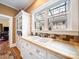 Charming kitchen featuring white cabinetry, tiled backsplash, and a bright window over the sink at 11 Tallassee St, Badin, NC 28009