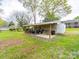 Backyard with a white outbuilding and covered storage area, with ample space for lawn maintenance equipment at 11 Tallassee St, Badin, NC 28009