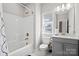 A cozy bathroom with white walls, a white shower-tub combo, brushed gold fixtures, and a gray vanity at 15126 Shallow Ridge Rd, Charlotte, NC 28278