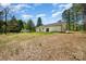 A wide shot of the home's backyard and patio space nestled within a green wooded tree line at 157 Fraley Rd, Gastonia, NC 28052