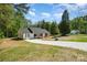 The home is white with a gray roof, a long driveway and green trees in the background of the surrounding property at 157 Fraley Rd, Gastonia, NC 28052