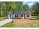 Traditional style, single story home with a black roof, white siding, a covered front porch and a long concrete driveway at 157 Fraley Rd, Gastonia, NC 28052