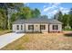 Charming single story home with a black roof, white siding, a covered front porch and a long concrete driveway at 157 Fraley Rd, Gastonia, NC 28052