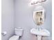 Powder room with pedestal sink, oval mirror, and light gray walls creates a clean and simple space at 15964 Cumnor Ln, Charlotte, NC 28277