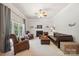 Cozy living room with a fireplace, comfortable leather seating, and natural light from a large window at 202 Weeping Spring Dr, Mooresville, NC 28115