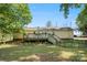 Backyard view with wooden deck featuring weathered stairs and lattice, leading to a spacious grassy yard with mature trees at 2115 Fowler Secrest Rd, Monroe, NC 28110