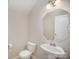 Cozy half-bathroom featuring pedestal sink, large mirror, and neutral wall color at 244 Aershire Ct, Concord, NC 28025