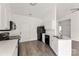 Well-lit kitchen with white cabinets, modern appliances, wood floors, and a view to the living room at 2659 Captains Watch Ne Rd, Kannapolis, NC 28083
