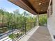 Spacious balcony with wood-look tile flooring, black metal railing, and wooded neighborhood views at 2909 Hanson Dr, Charlotte, NC 28207