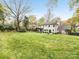 Spacious backyard showcasing a well-maintained lawn, mature trees, and the home's exterior with a covered patio at 2912 Wheelock Rd, Charlotte, NC 28211