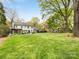 Expansive backyard with lush green lawn, mature trees, play set, and the rear exterior of the home at 2912 Wheelock Rd, Charlotte, NC 28211