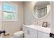 Bathroom with modern white vanity, round mirror, and a window view at 314 Bass Ln, Charlotte, NC 28270