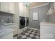 Well-equipped laundry room featuring modern washer, dryer, sink, and cabinetry with stylish checkerboard floors at 3160 Ashwood Park Dr, Belmont, NC 28012