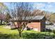 Back exterior view featuring a brick house with patio, fenced yard, and mature trees at 394 Efird St, Gastonia, NC 28054
