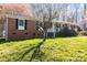 Traditional brick home featuring a covered front porch and black shutters, set on a green lawn with mature trees at 394 Efird St, Gastonia, NC 28054