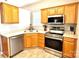 Kitchen with stainless steel appliances, tiled floor, and warm-toned cabinets and countertops at 4130 Town Center Rd, Harrisburg, NC 28075