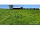 Picturesque barn with weathered exterior, set amidst a vibrant green field under a clear sky at 5373 Nc Hwy 16 N Hwy, Taylorsville, NC 28681