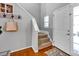 Bright foyer featuring hardwood floors, a staircase with carpeted steps, and a coat rack on the wall at 6115 The Meadows Ln, Harrisburg, NC 28075