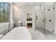 Elegant bathroom featuring a tub, a glass-enclosed shower, and a doorway leading to a bedroom offering a convenient layout at 6654 Maple Spring Ct, Denver, NC 28037