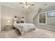 Cozy bedroom with carpet, a large window, a unique headboard, and a ceiling fan enhancing comfort and style at 6654 Maple Spring Ct, Denver, NC 28037