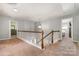 Bright hallway featuring neutral paint, carpet, and a staircase with white railing and wooden accents at 9013 Gailes Dr, Charlotte, NC 28278