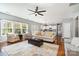 Bright, open living room featuring hardwood floors, a ceiling fan, and natural light from a wall of windows at 9013 Gailes Dr, Charlotte, NC 28278