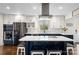 Well-lit kitchen boasts white cabinets, navy blue island, stainless steel appliances, and quartz countertops at 9718 Barkridge Rd, Mint Hill, NC 28227