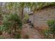 Brick home's backyard with mature landscaping, stone pathway, and grill at 104 Chalfont Ct, Salisbury, NC 28147